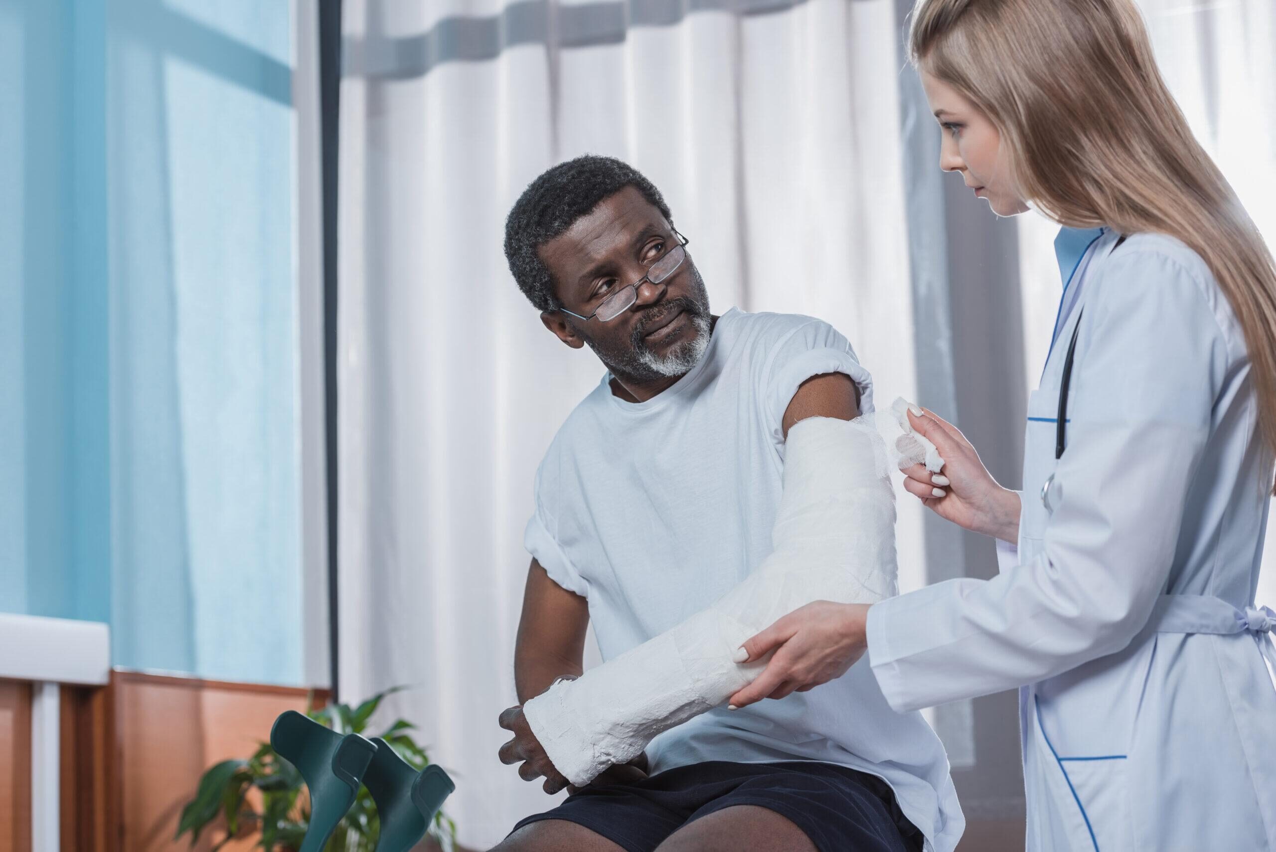 Doctor bandaging african american patient hand wit