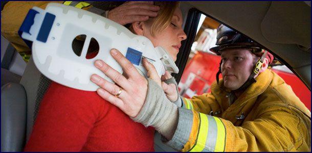 Emergency responders assist an injured passenger in a car accident, fitting a neck brace.